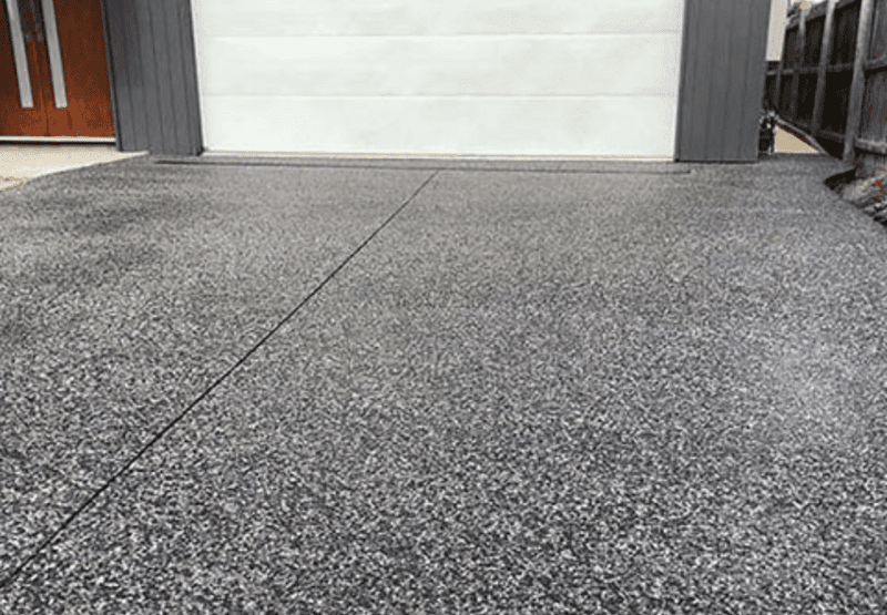 A freshly cleaned concrete driveway in front of a Vancouver home surrounded by greenery