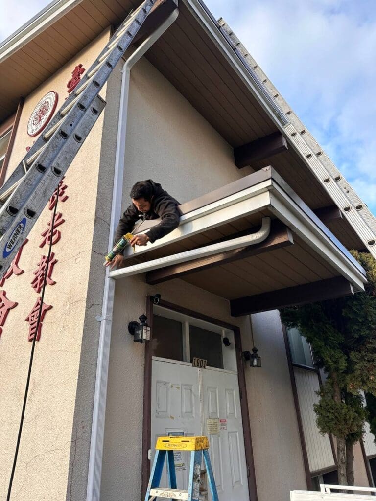 Experienced gutter handyman cleaning and repairing a home's gutters.